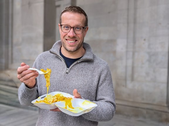 Tour guide eating chips, cheese, and curry sauce