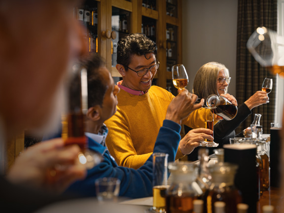 People at a bar smiling and tasting whisky