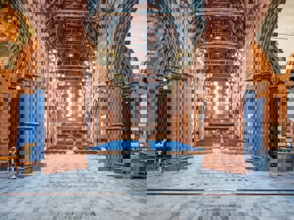 Gothic style grand hall set up for a conference with rows of blue chairs. 