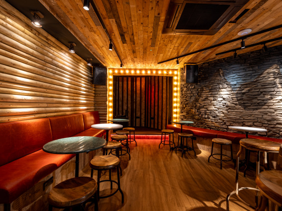 Small event room at Wunderbar West End, red curtains and lights surround a small stage. 