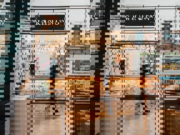 Black mental doorframe with sign above that read The Grahamston Bar. View through doorway to marble,, glass and brass bar. 