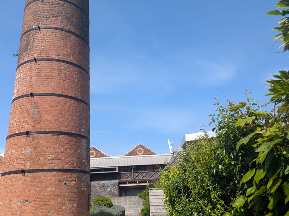 External view of a large brick tower with path leading to gardens and hedges 