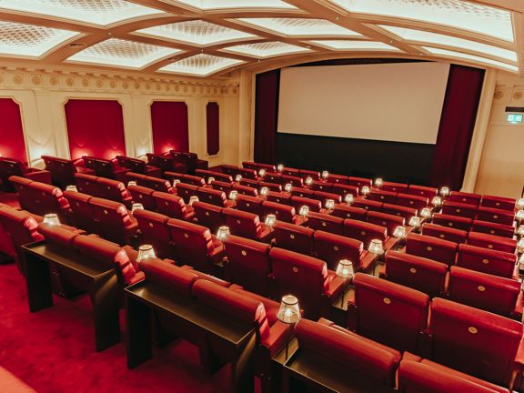 Cinema with red leather couches and plush red carpets. 