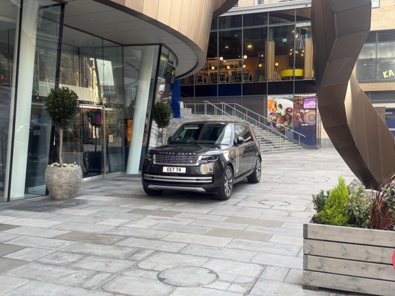 Black Ranger Rover in front of a modern glass and metal building.