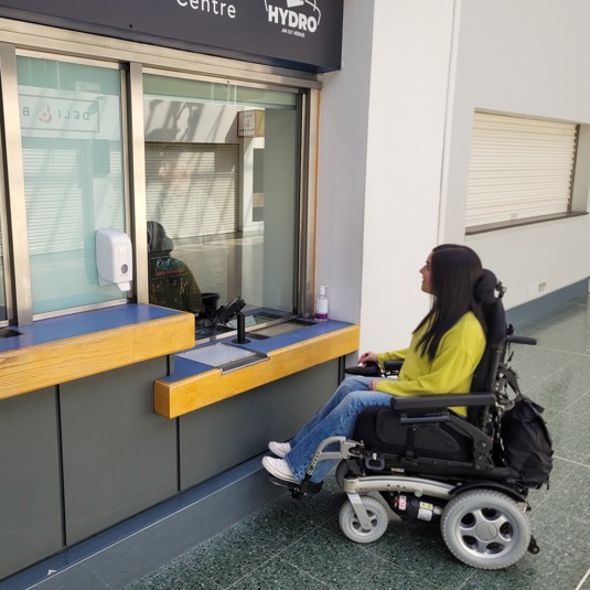 Wheelchair user in front of information desk at the Scottish Event Campus