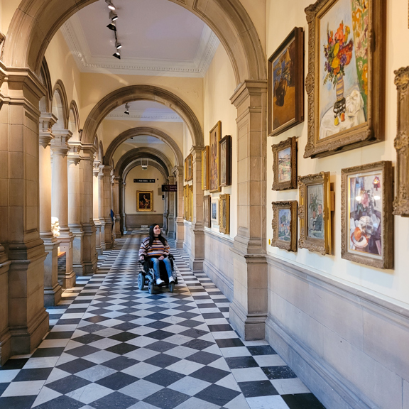 Person in wheelchair in the galleries of Kelvingrove Art Gallery and Museum