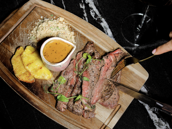 Wooden platter of grilled beef and pineapple