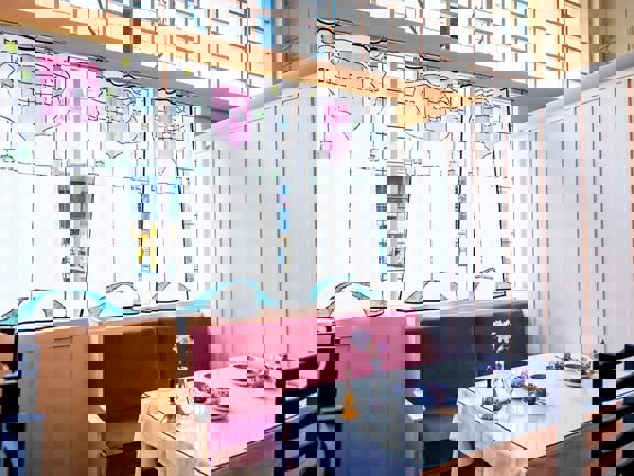 Mackintosh Tearoom window dressed with white muslin curtains with an Mackintosh style pint and green screen print. 