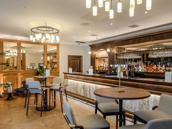 The Exchange Bar area - high stools at high tables, marble front bar with wooden bar and table tops. 