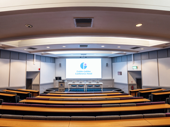 Rows of seats forming an auditorium facing a large screen.