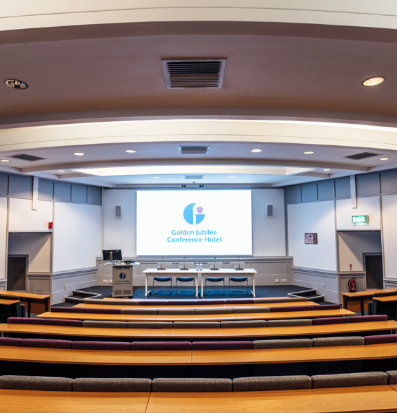 Rows of seats forming an auditorium facing a large screen.