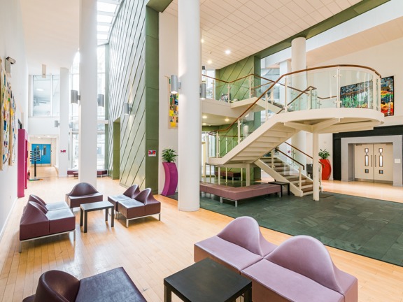 Foyer of The Boardwalk venue. Central curving staircase, high ceilings, light and bright area with occasional seating.