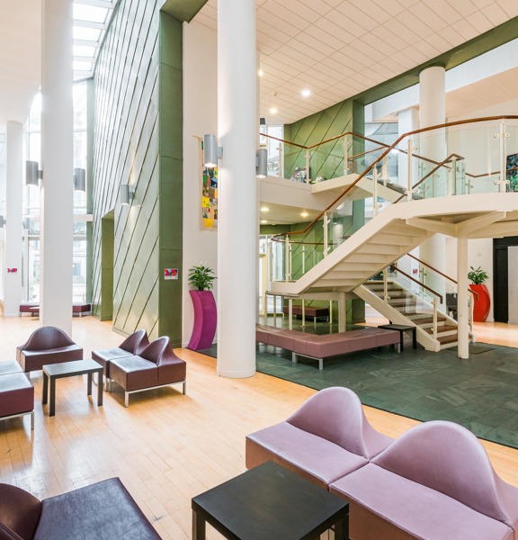 Foyer of The Boardwalk venue. Central curving staircase, high ceilings, light and bright area with occasional seating.