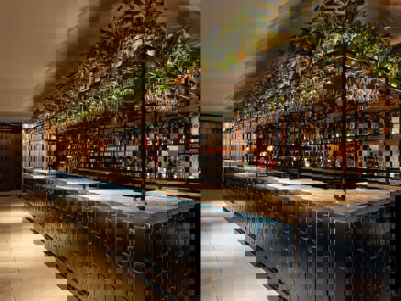 Radisson Blu hotel bar with dark blue tiled front with black mental frame above and wine glasses hanging above.