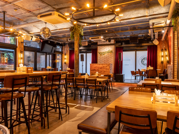 Large event space, wooden tables and leather chairs. Silver glitter ball hanging from the ceiling and red drapes hanging in the windows.
