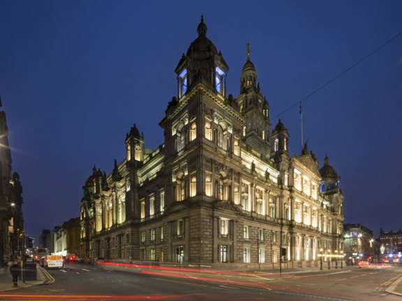 Corner view of Glasgow City Chambers lit up at night. 
