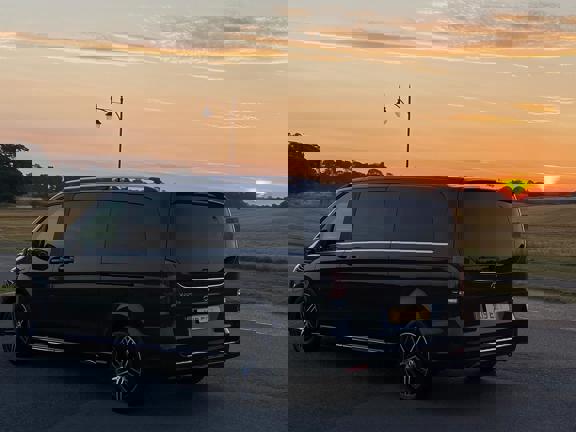 Mercedes people carrier driving away, sun setting in the background. 