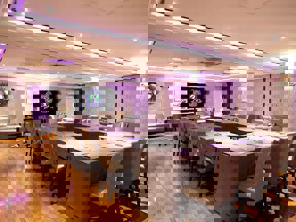 Conference room with large hollow table set up and leather chairs around the table. 