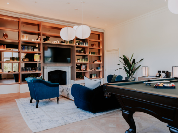 Modern hotel suite set within a heritage building - marble fireplace, cornicing, Parque flooring, velvet sofas, contemporary wooden bookshelves and pool table.  
