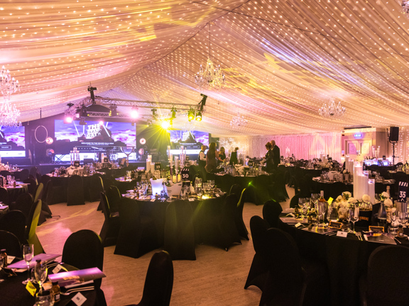 Marque with a white ceiling with chandeliers, round table with black tablecloths 
