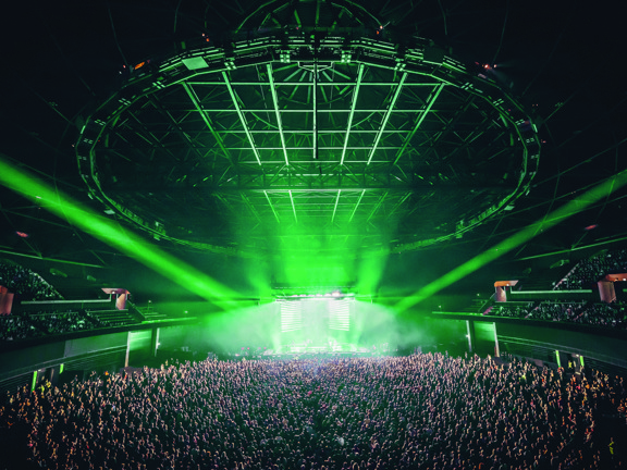 View of OVO Hydro stage during busy concert, illuminated in green light.