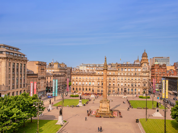 sunny view of George Square with a 24m column in the centre with a statue of Sir Walter Scott