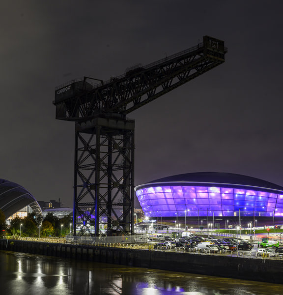 A nightscape scene of the OVO Hydro lit up and the Finneston Crane