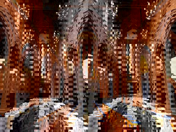 The Grand Hall at The Barony set up with three long tables running the length of the room. Another long table runs across the top of the room from left to right.  All are covered with white table linen and flowers.