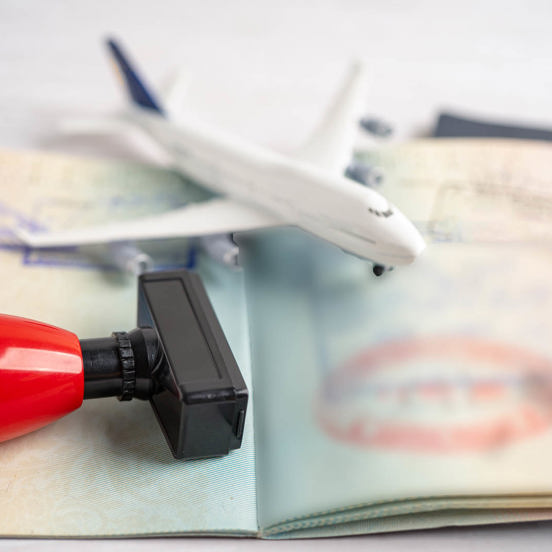 open passport with a rubber stamp and a small toy airplane on it