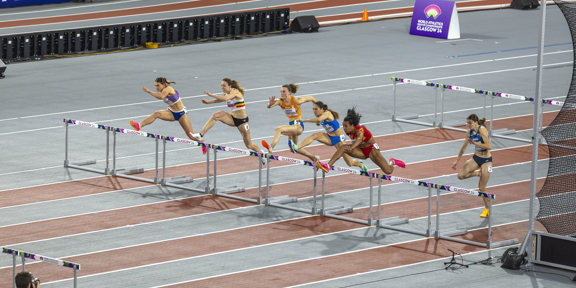 Six athletes leap over hurdles