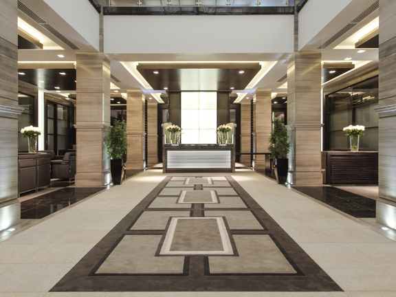 200 Conference & Events Ltd Grand Hall. A large, symmetrical entrance area decorated in muted tones, there are potted plants and vases of cut flowers decorating the reception desk
