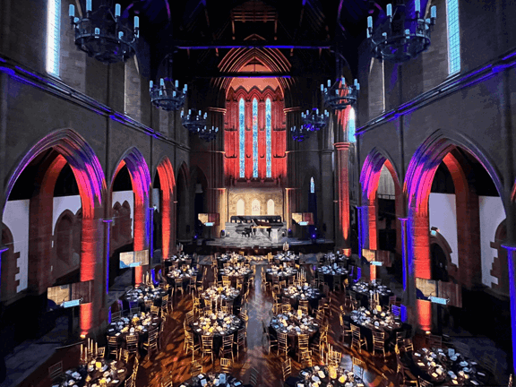 The Grad Hall at The Barony set up for a dinner. Blue and red lighting lights up the gothic style arches in the room.