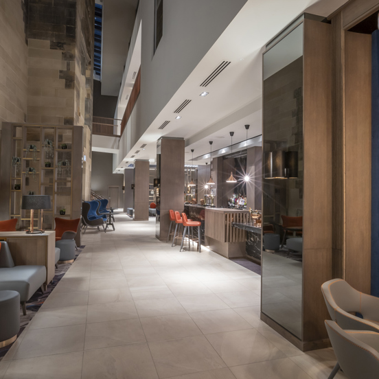 Hotel bar with mixed seating and a modern wooden bar on the left hand side. 