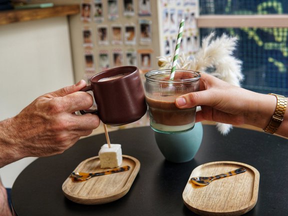 Two people cheersing with coffee cups.