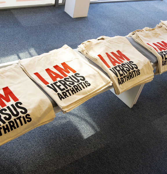 Row of tote bags reading I am Versus Arthritis