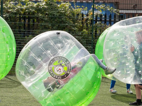People inside a giant inflatable football during a football game.