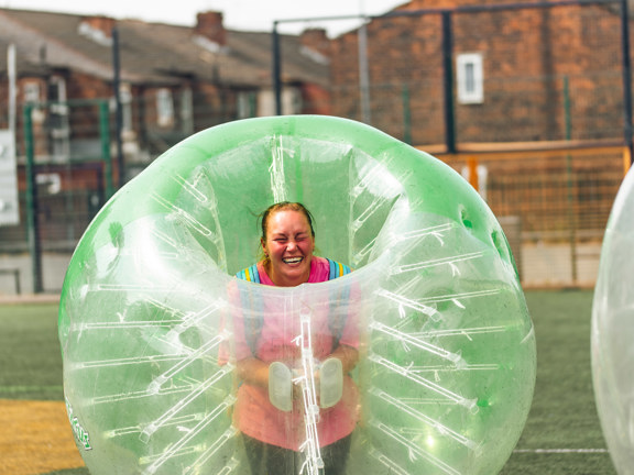 Woman laughing while peering out of a giant inflatable football.