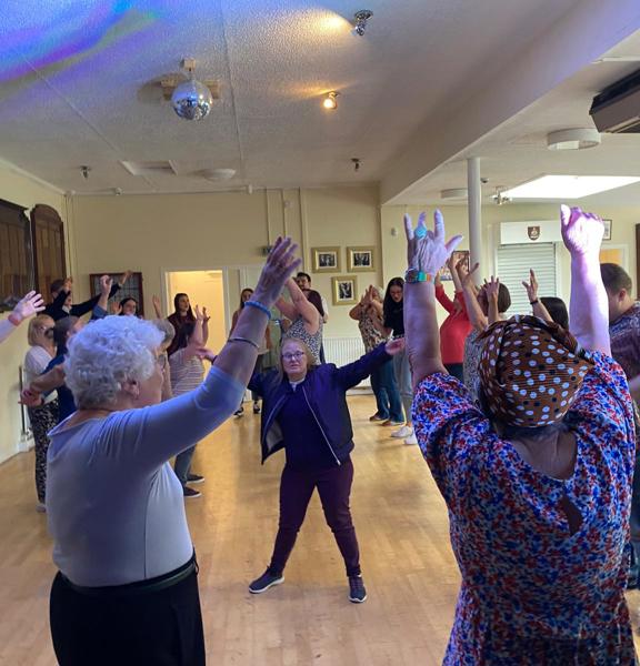 A group of people are gathered and have their arms up in the air dancing