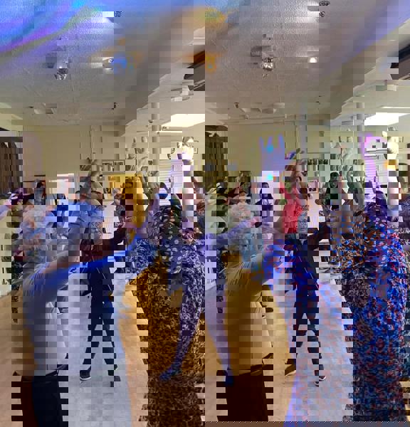 A group of people are gathered and have their arms up in the air dancing