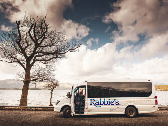 Person stepping off a Rabbie's mini coach at a loch 