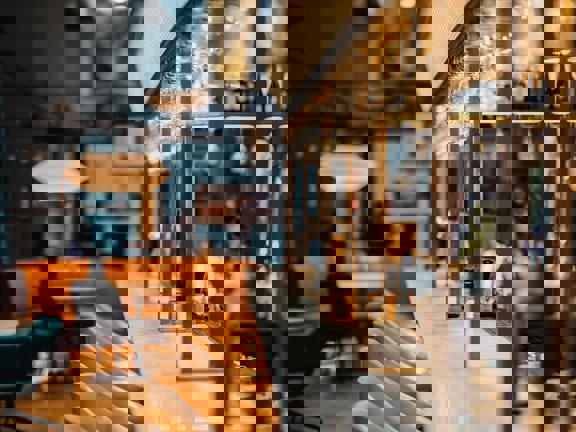 Marble topped bar with brass metal framework above and beige leather barstools lined up along one edge.