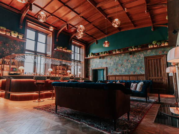 Modern hotel bar set within a heritage property - Parque flooring, wooden vaulted ceiling, velvet furnishings, modern wood and metal bar softly light with lamps and glass pendants.