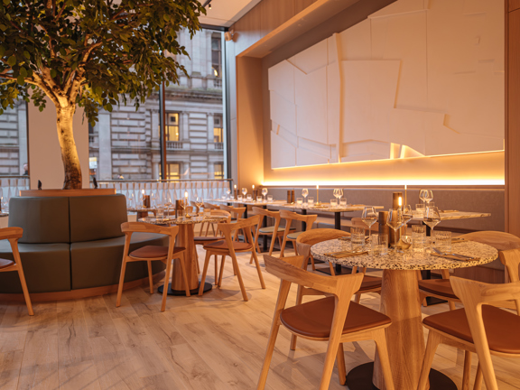 Bistro with light wooden furniture and flooring, full height windows and Hazel tree in centre.