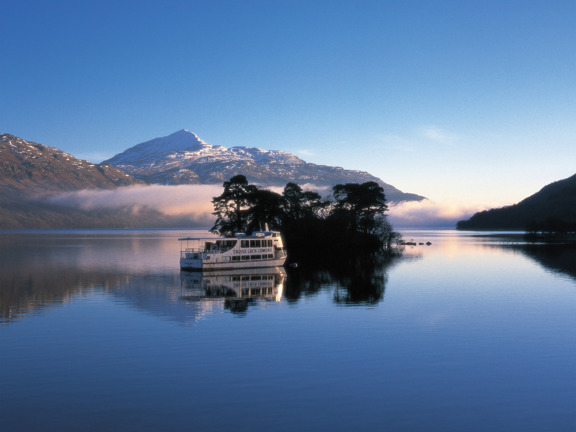 Boat on blue Loch Lomond with snowy hill in the background