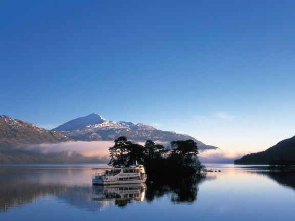 Boat on blue Loch Lomond with snowy hill in the background