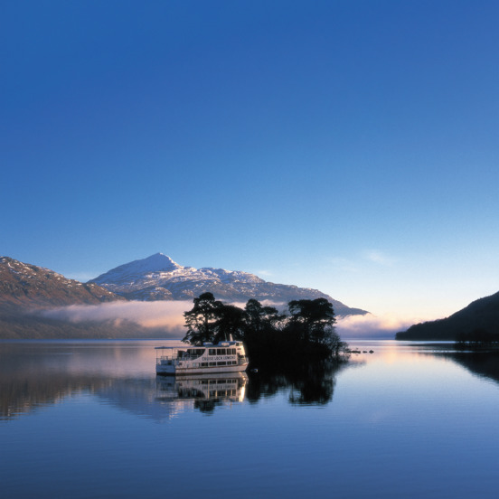 Boat on blue Loch Lomond with snowy hill in the background