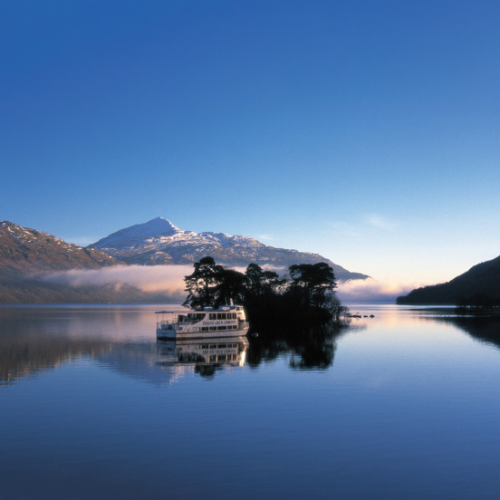 Boat on blue Loch Lomond with snowy hill in the background