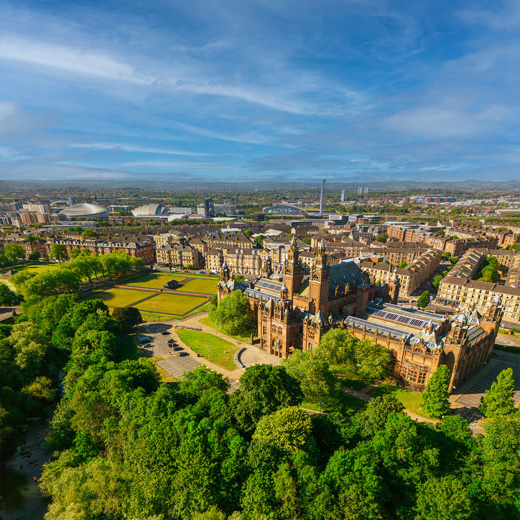 Glasgow cityscape, with the Baroque-style Kelvingrove Art Gallery and Museum, surrounded by greenery. The modern buildings of the Scottish Event Campus and the Glasgow Science Centre are visible in the background