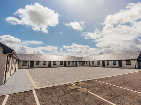 Newly built cottages in a u-shaped around a central courtyard on a bright sunny day with blue skies.