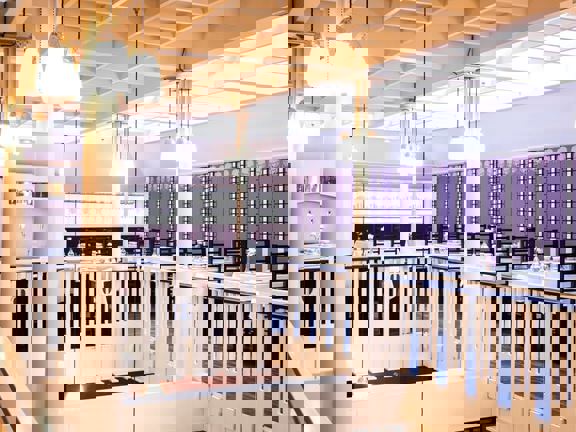 Tearoom gallery with mauve walls, ornate banister and glass lights hanging from the ceiling. 